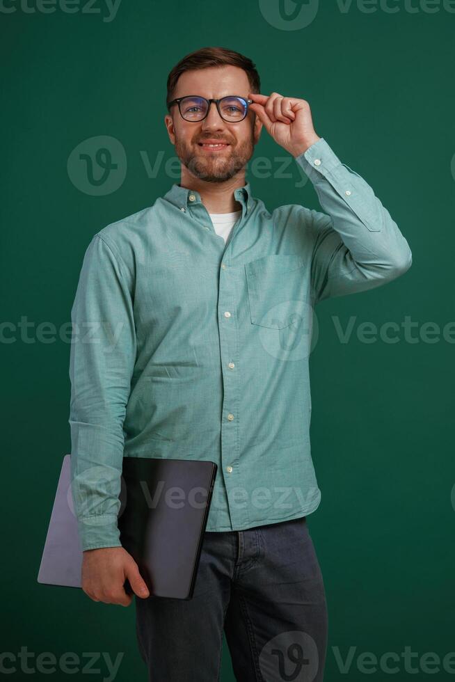 Business guy with laptop and glasses. Man is standing against background in the studio photo