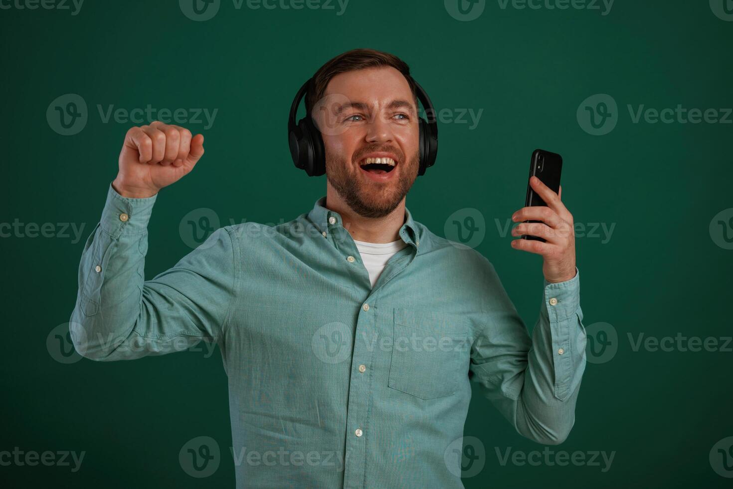 Smiling,, enjoying music. Man is standing against background in the studio photo