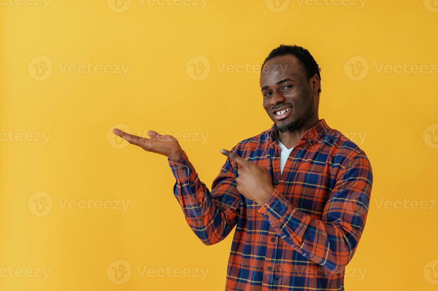Showing to the side for copy space.. Black man is in the studio against yellow background photo