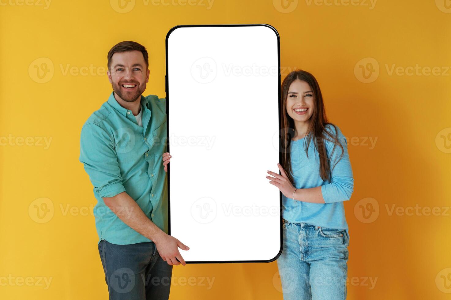 Holding ,white, display of smartphone, copy space. Man and woman are standing against yellow background photo
