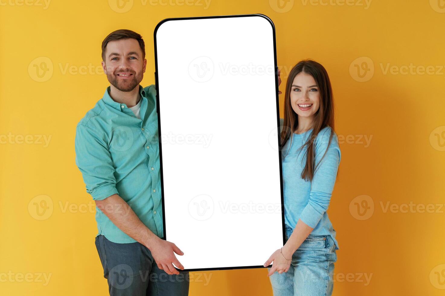 Holding, white display of smartphone, copy space. Man and woman are standing against yellow background photo