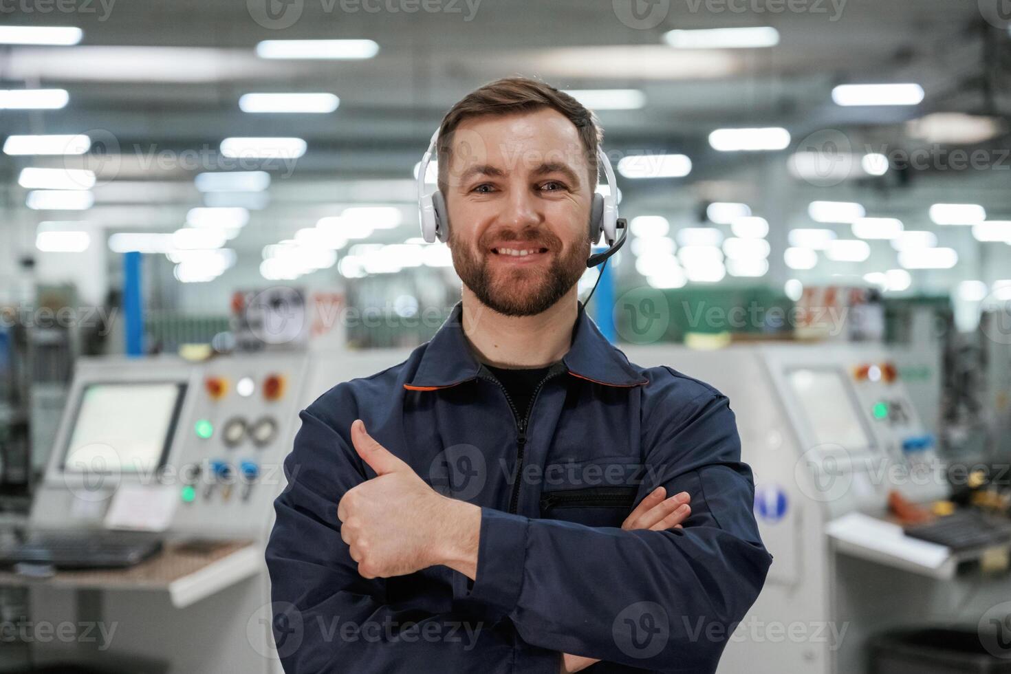 Standing and smiling. Factory worker is indoors with hard ,,hat photo