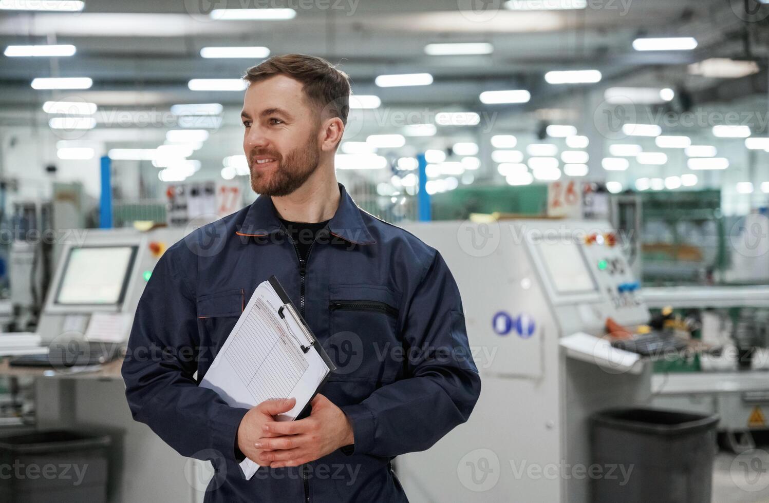 Standing and smiling. Factory worker is indoors with hard ,hat photo