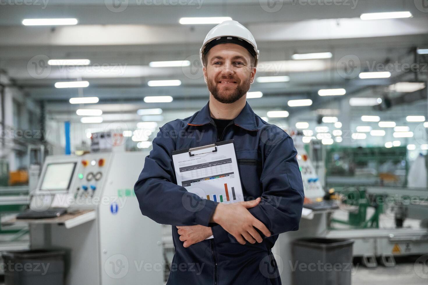 Happy ,,with results, holding graphs... Factory worker is indoors with hard hat photo