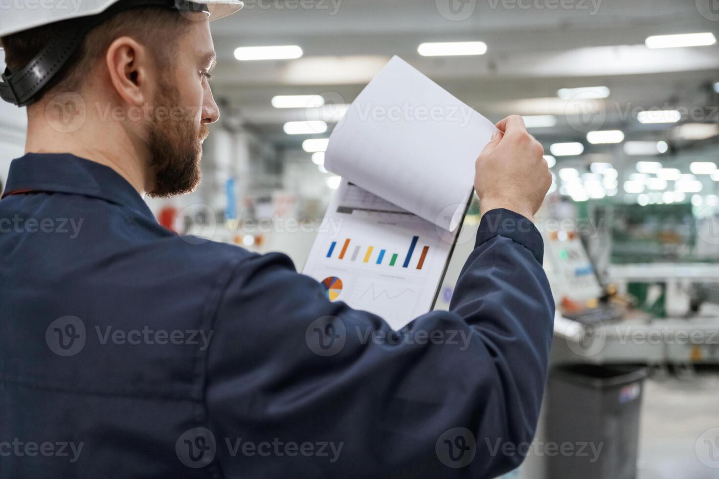 Turning, the, pages of documents. Factory, worker is indoors with hard hat photo