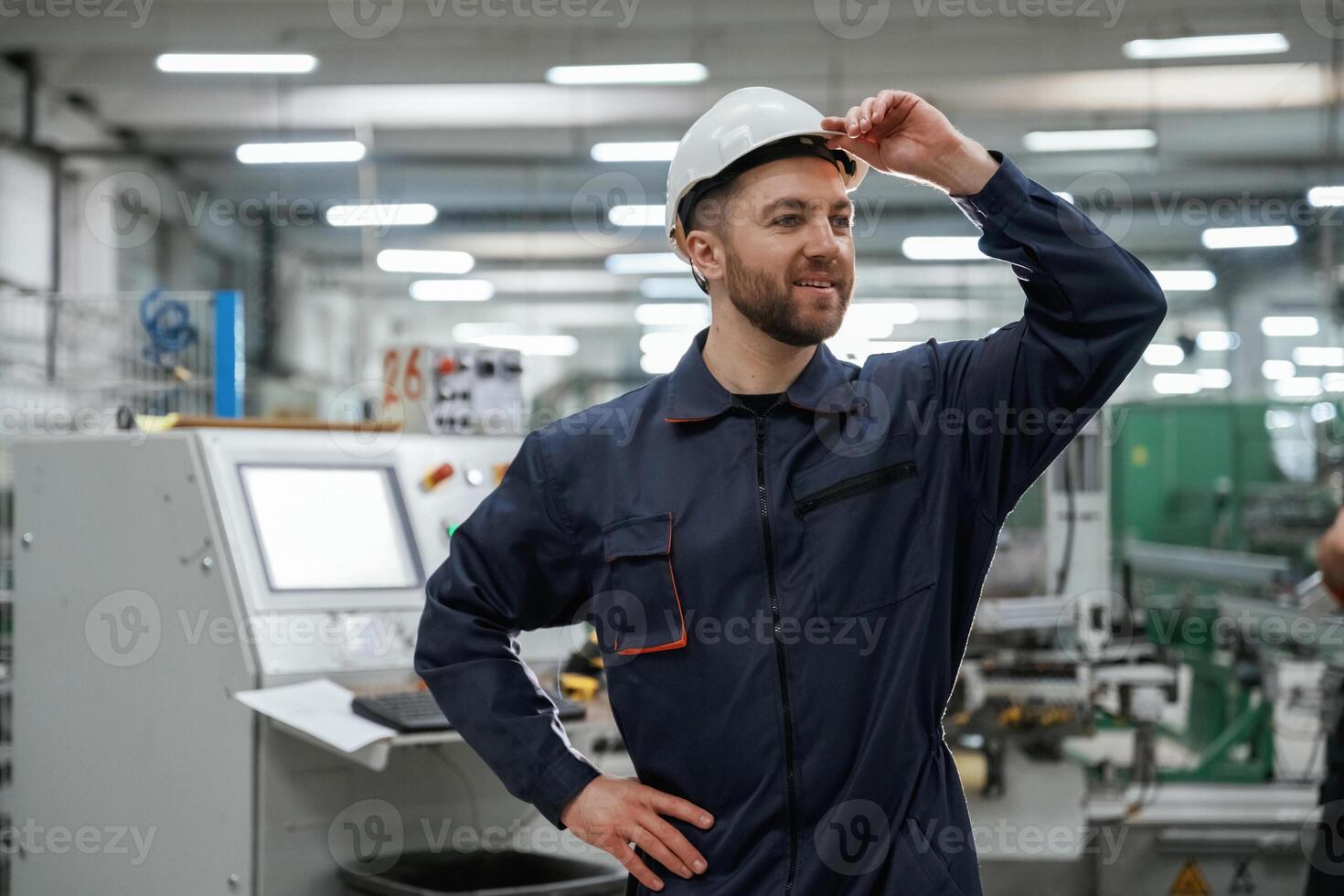 Employee, is looking far,, away. Factory worker is indoors with hard hat photo