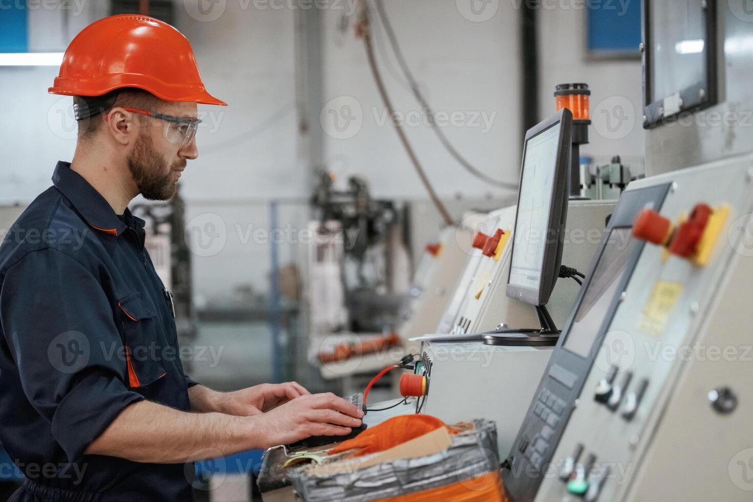 Side view, operating the machine. Factory worker is indoors with hard hat photo