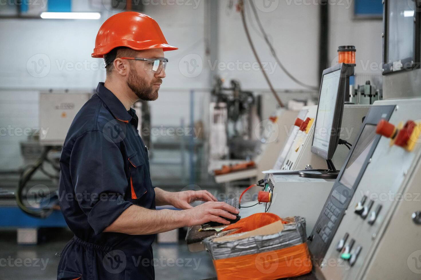 Operating, the machine,. Factory worker is indoors with hard hat photo