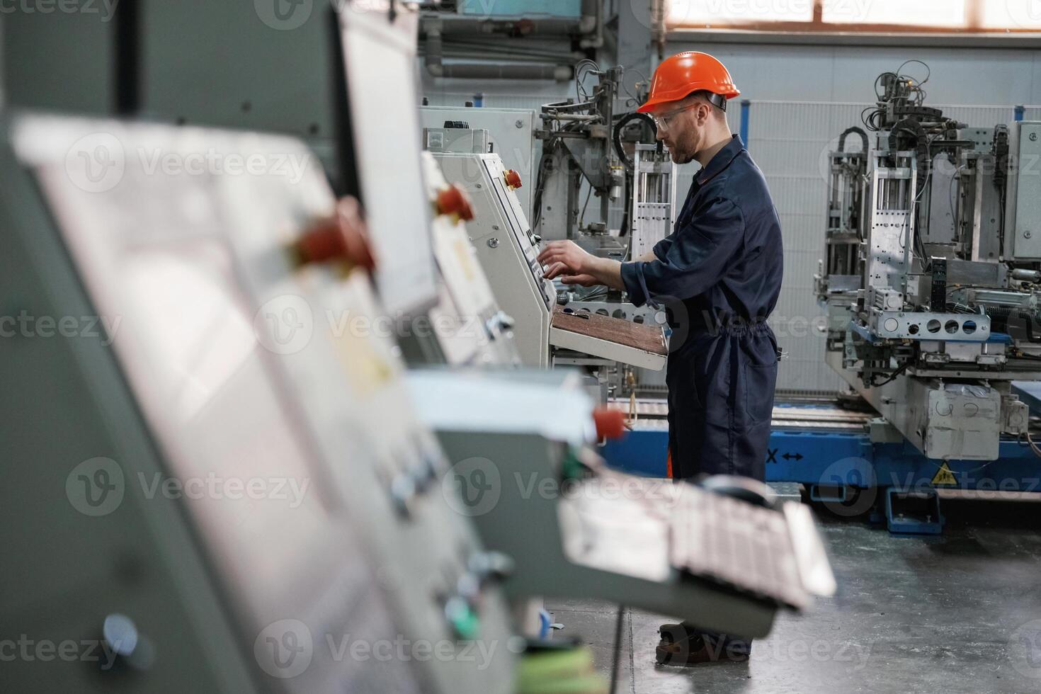 View ,from the side,, working with machine, operator. Factory worker is indoors with hard hat photo