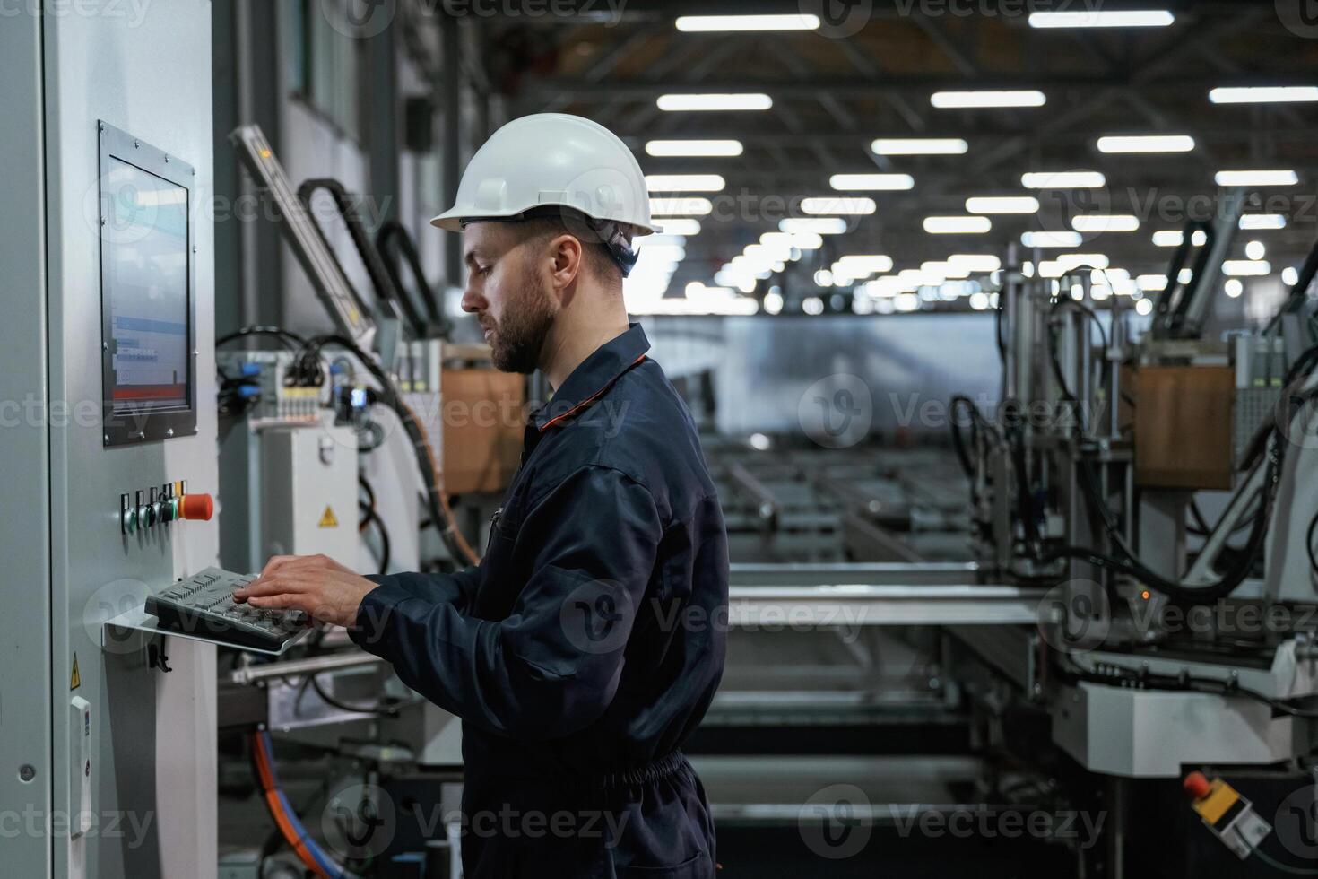 Adjusting ,settings ,,of machine, operating. Factory worker is indoors with hard hat photo