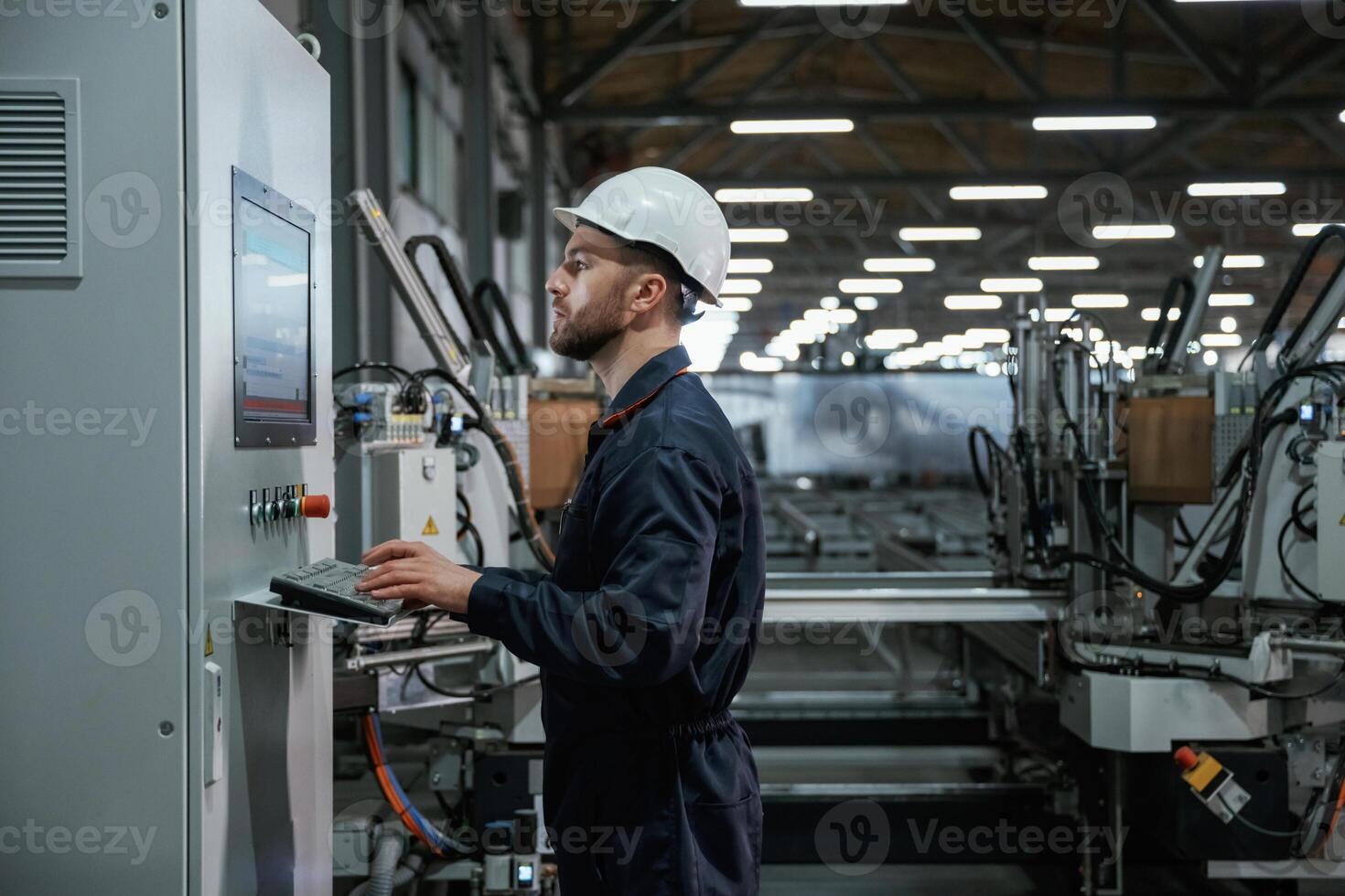 Using ,equipment,, operator. Factory worker is indoors with hard hat photo