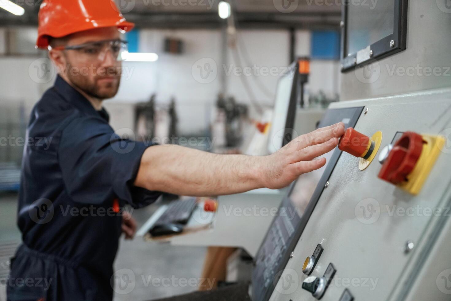 View from the,side, working with machine, operator. Factory worker is indoors with hard hat photo