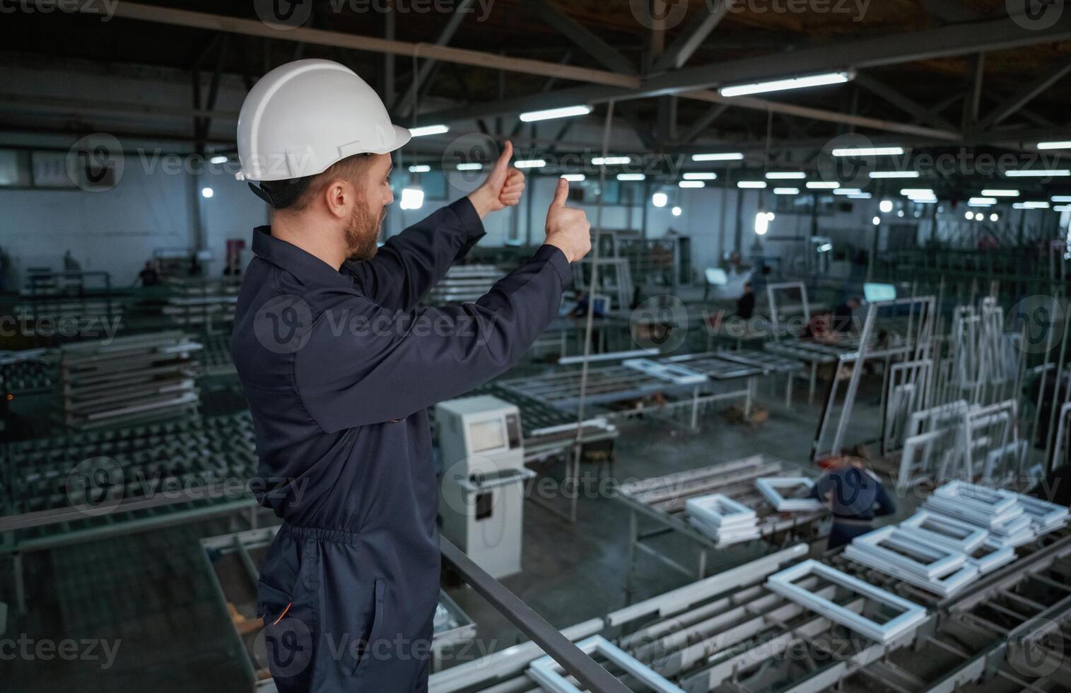 Gesture ,of thumb, up. Factory worker is indoors with hard hat photo