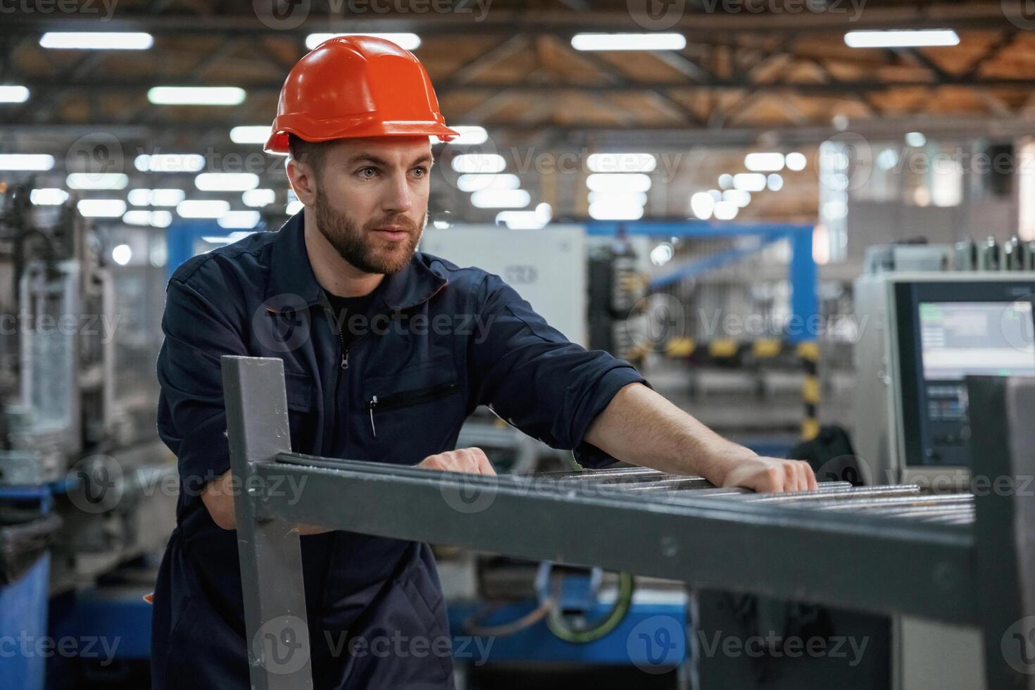 Working with machinery... Factory worker is indoors with hard hat photo