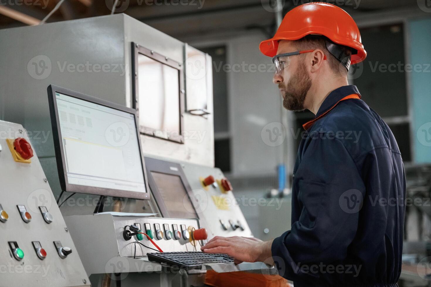 Operating, the, machine. Factory worker is indoors with hard hat photo