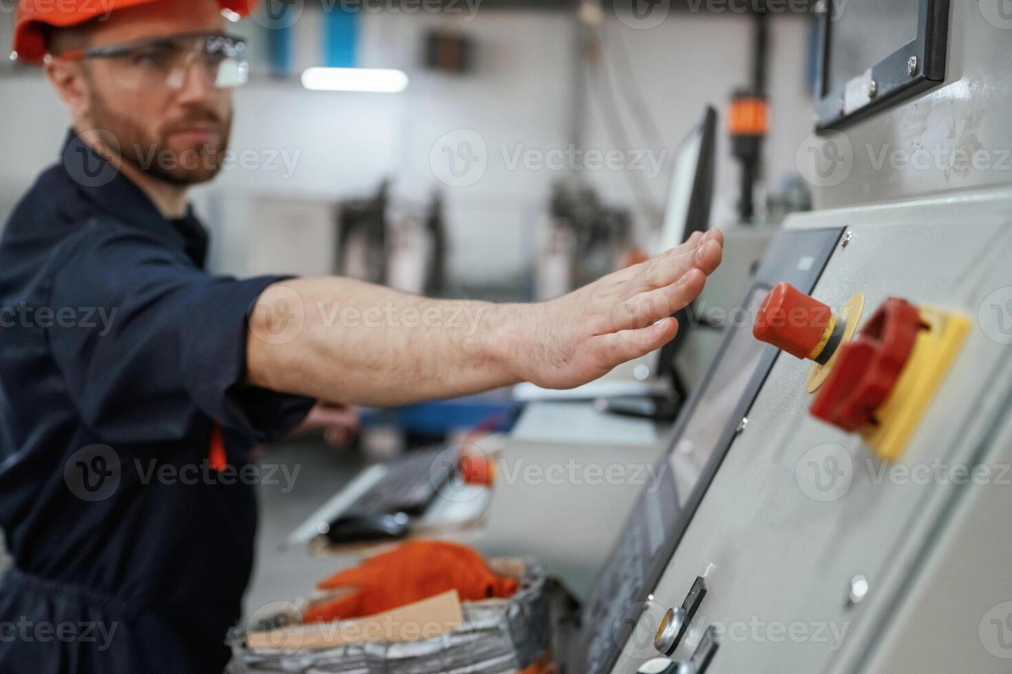 Side view, operating, the, machine. Factory worker is indoors with hard hat photo