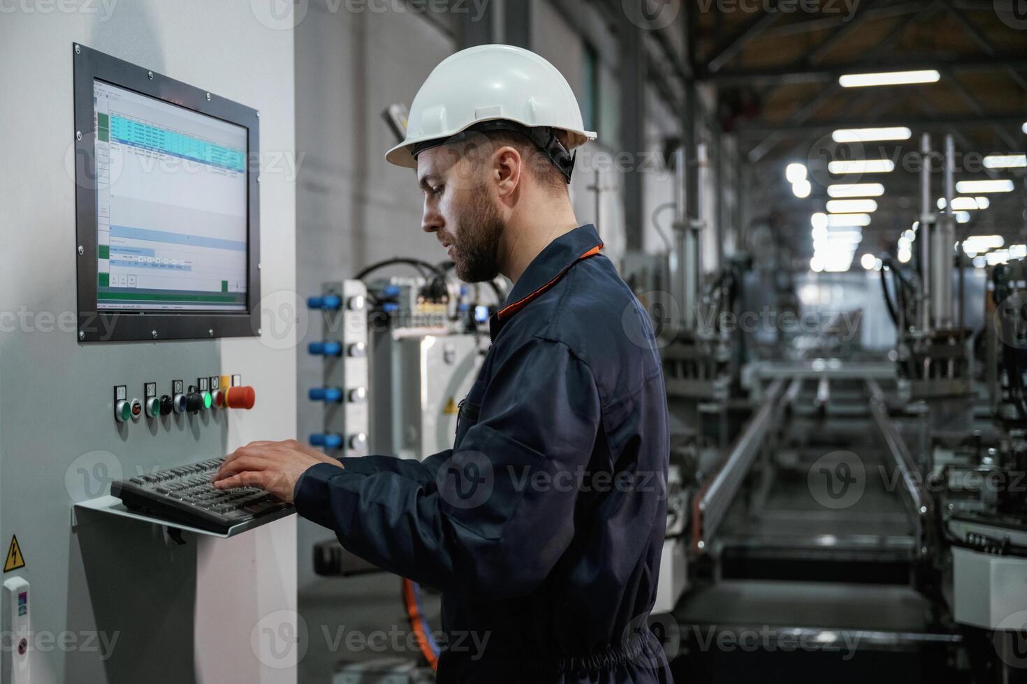 Adjusting settings ,of machine, operating. Factory worker is indoors with hard hat photo