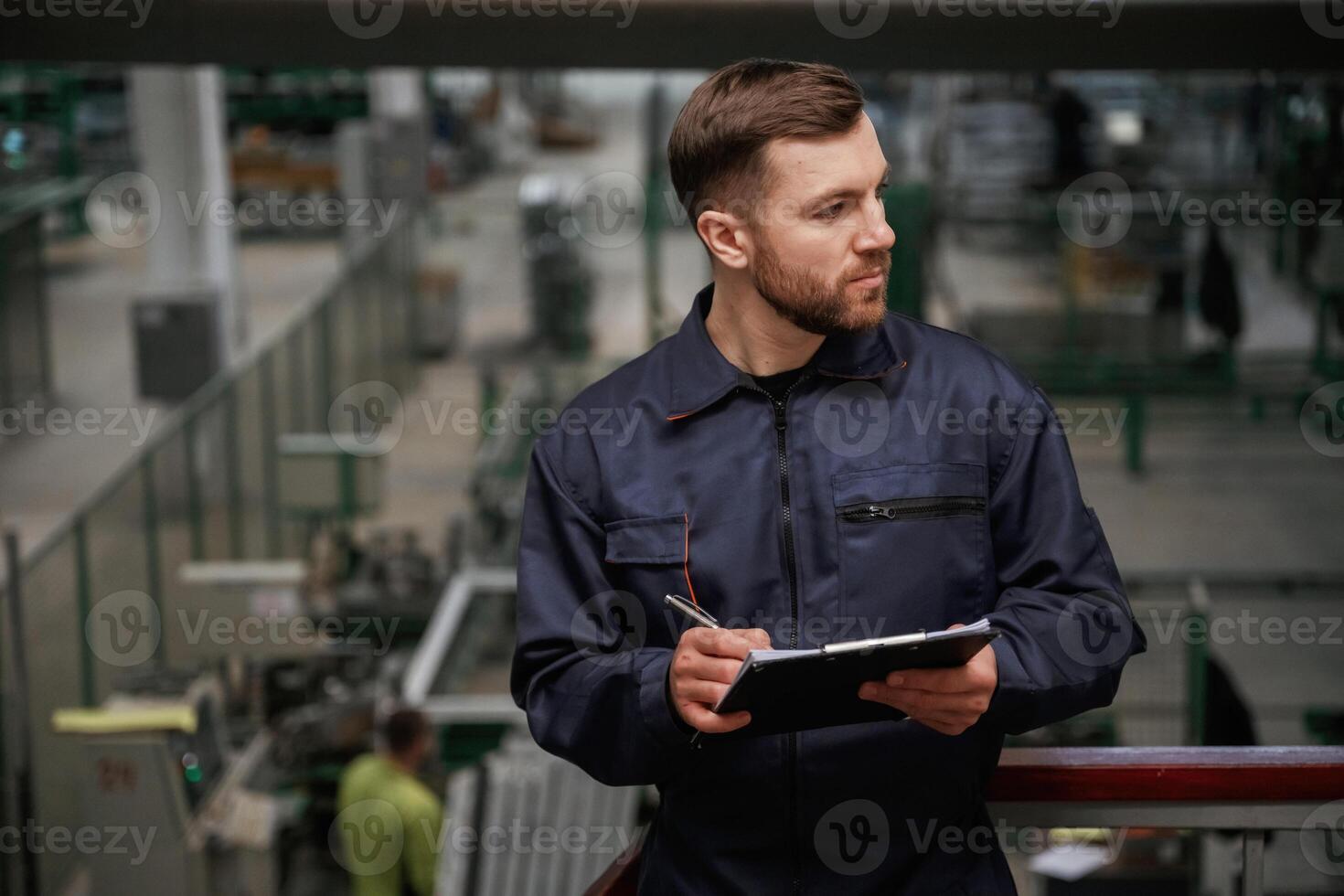 Writing ,,information into the notepad. Factory worker is indoors with hard hat photo