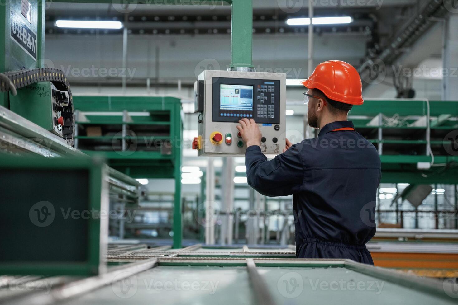 Green colored ,machine,, operator is busy. Factory worker is indoors with hard hat photo