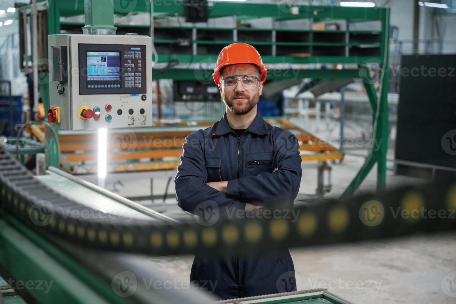 Beautiful ,man is standing with arms crossed. Factory worker is indoors with hard hat photo