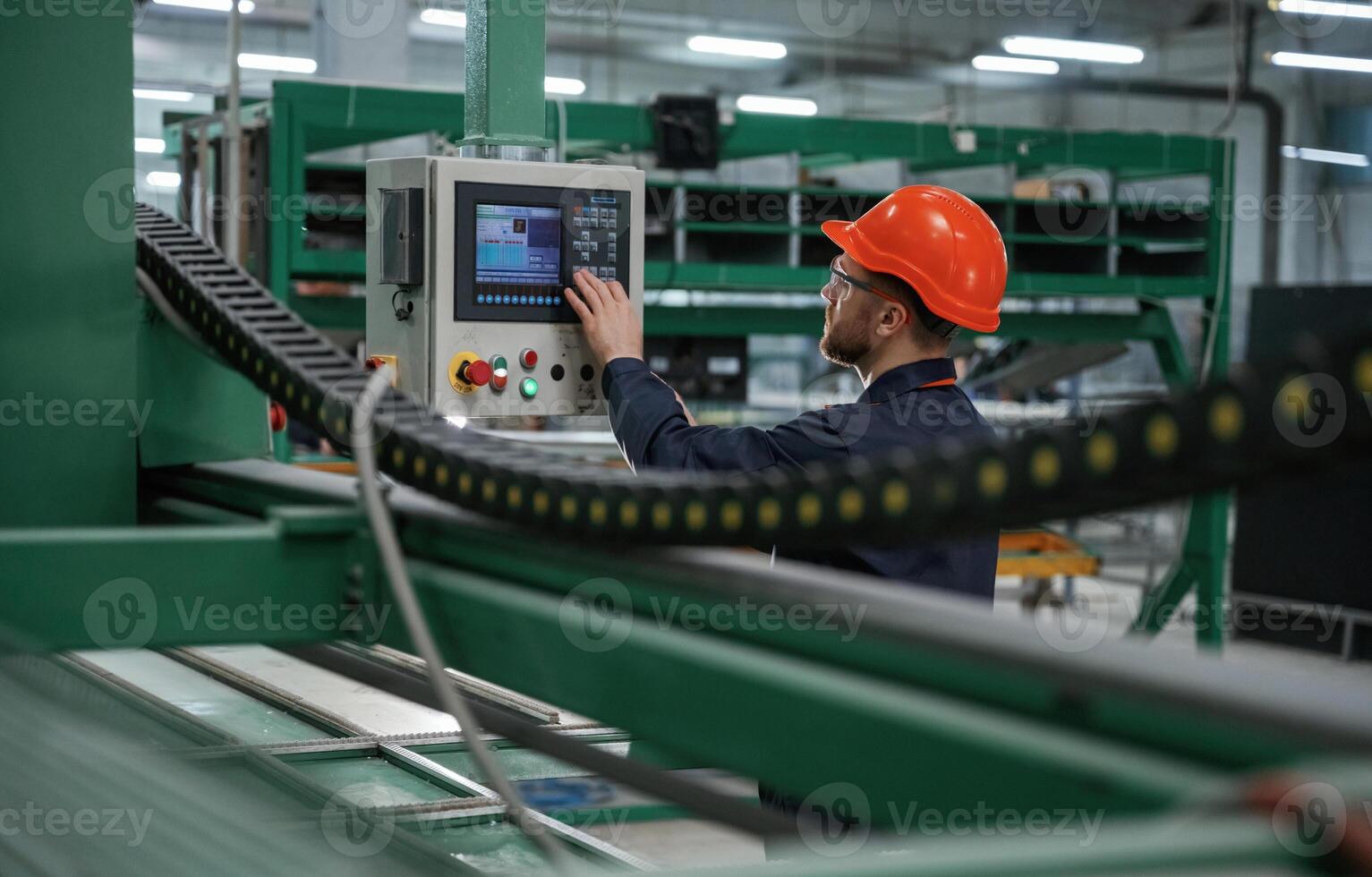 Green,, colored ,machine, operator is busy. Factory worker is indoors with hard hat photo