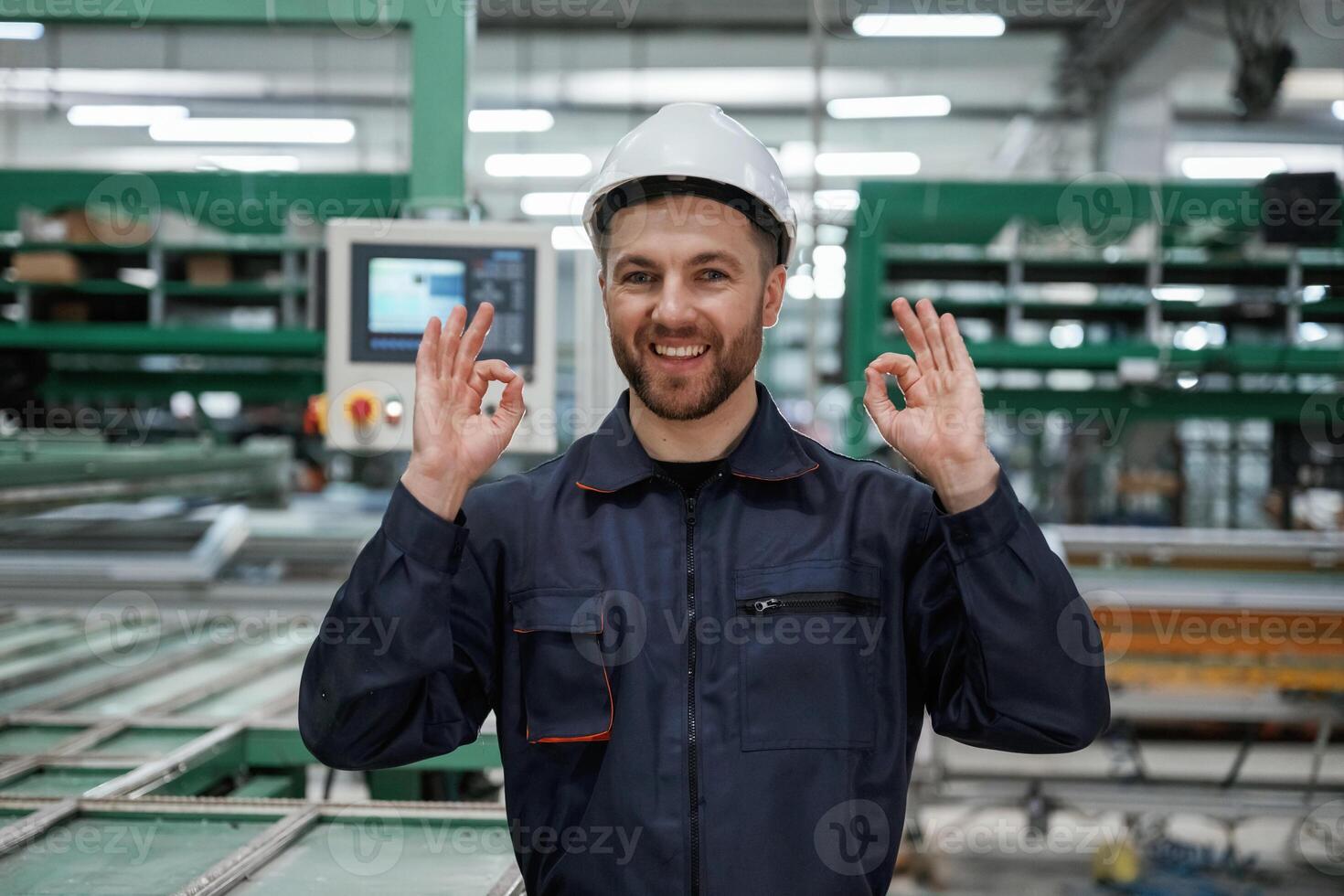 Against,, machine. Factory worker is indoors with hard hat photo