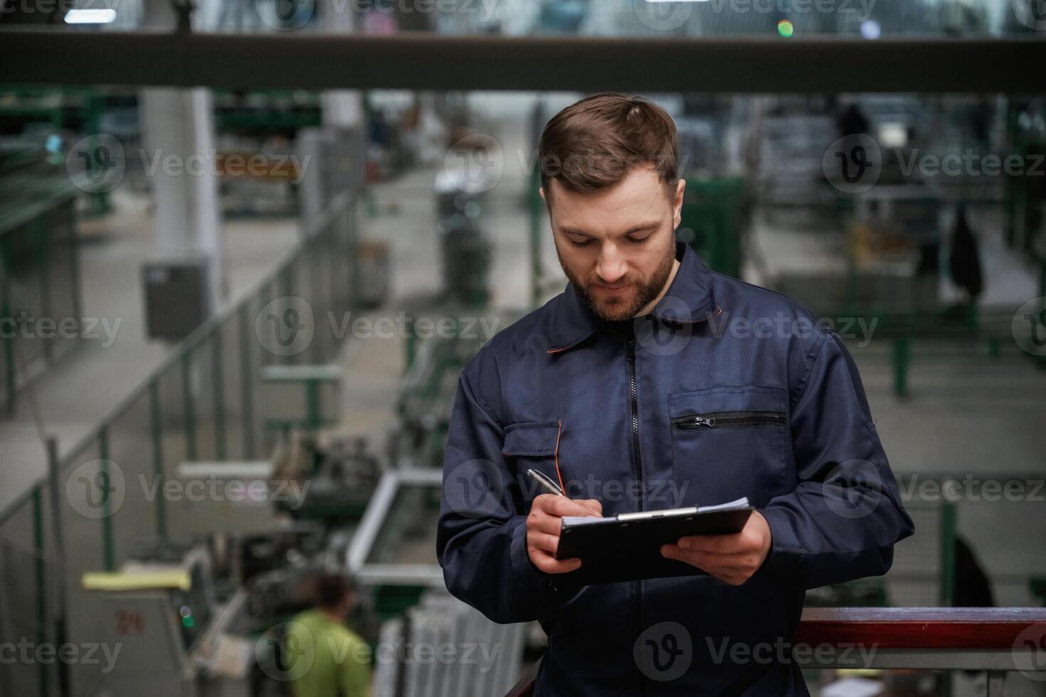 Writing ,information into the notepad. Factory worker is indoors with hard hat photo
