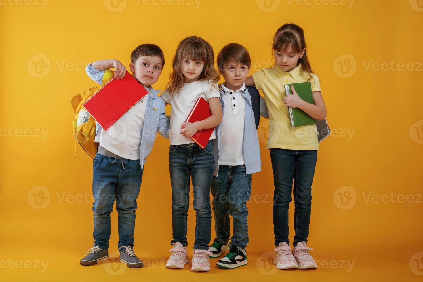 Notepads in hands,, conception of education. Kids are together against yellow background photo
