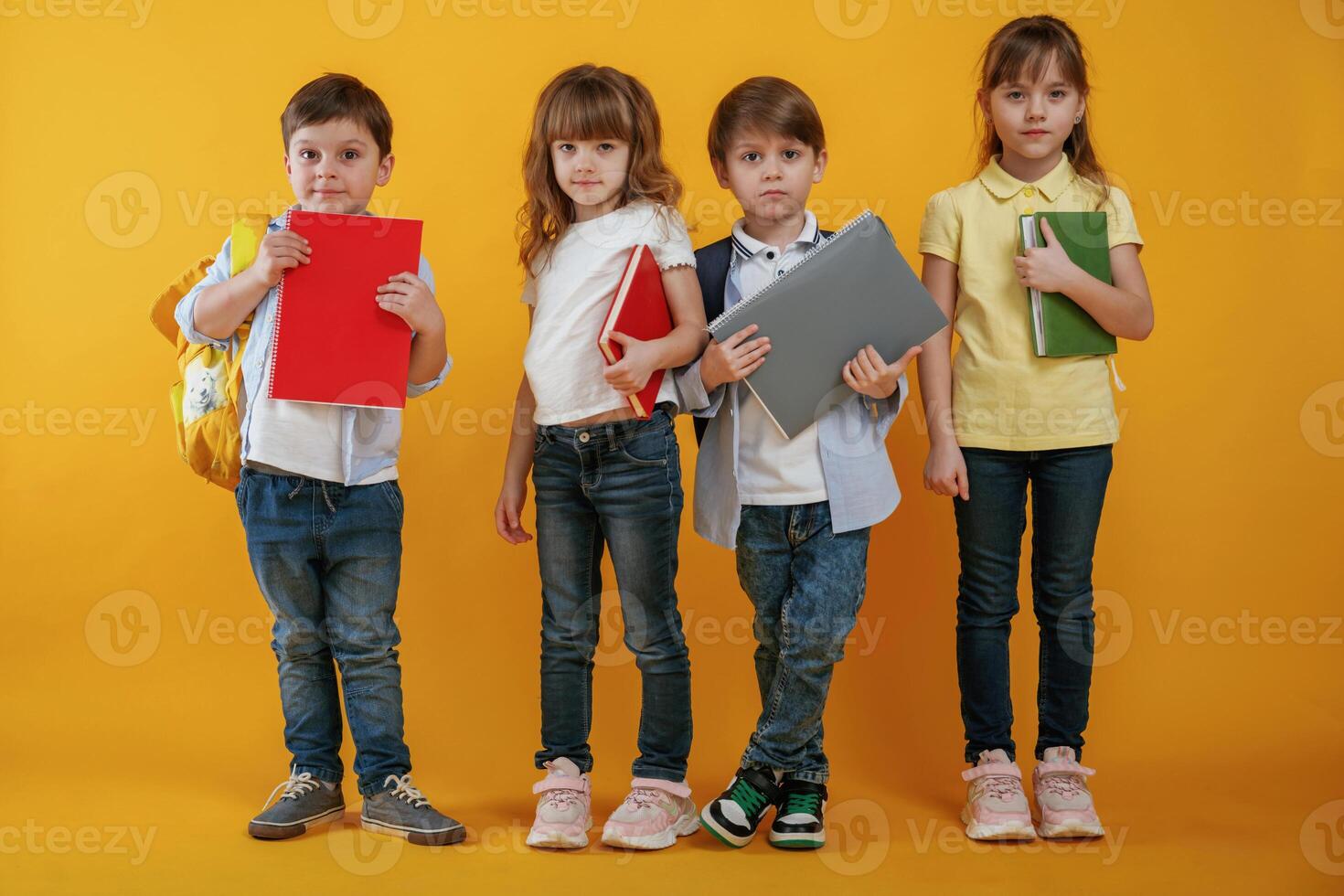 Notepads, in hands, conception of education. Kids are together against yellow background photo