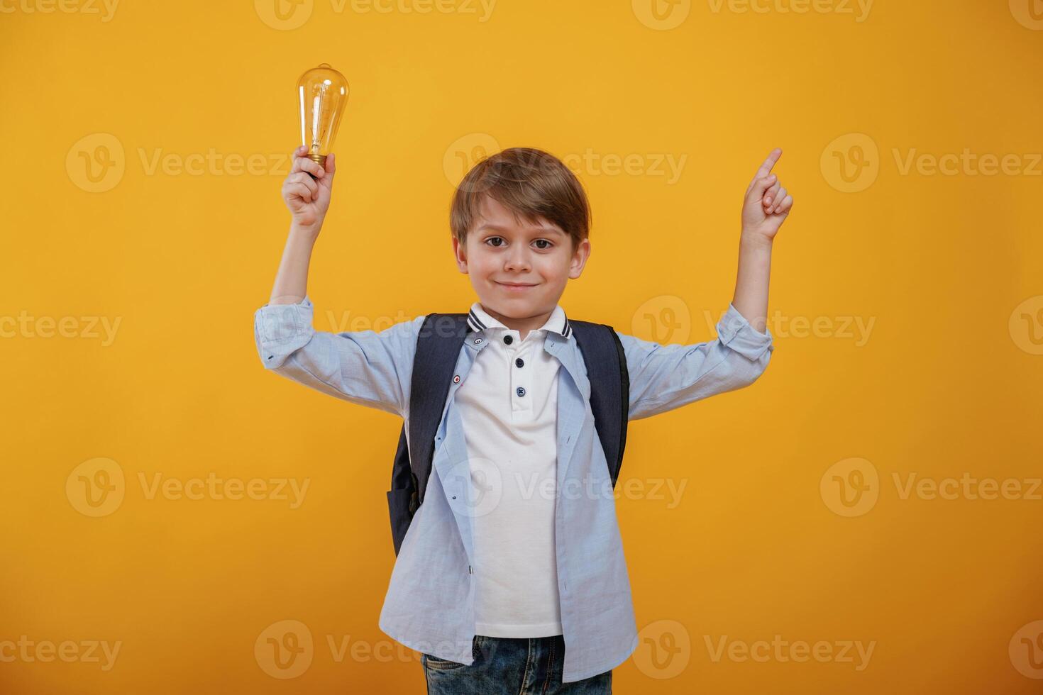 Light ,bulb in,hand. Conception of smart person and idea. Little boy is in the studio against yellow background photo