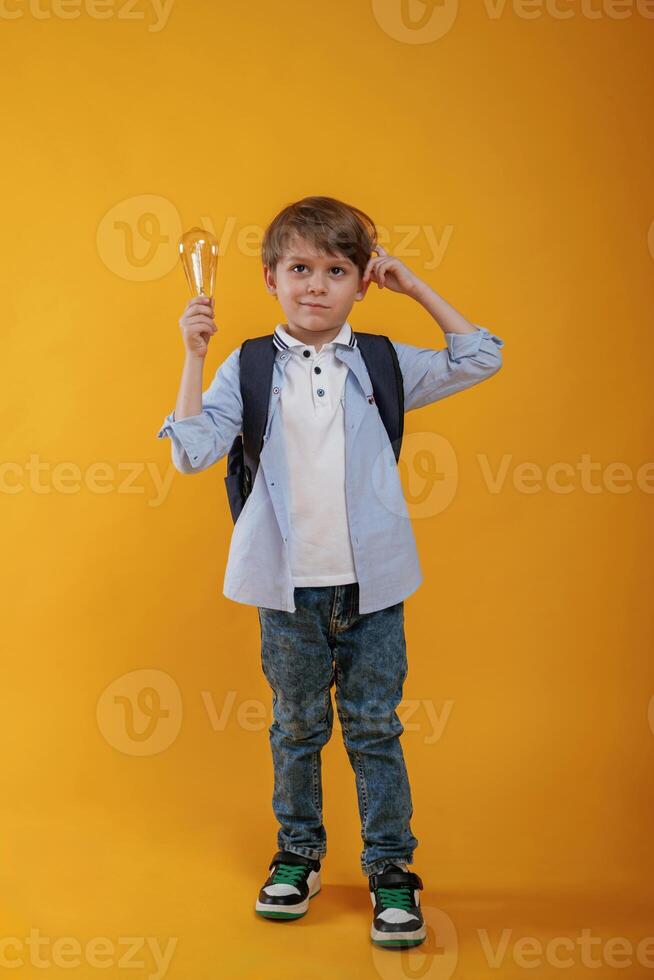 Light bulb ,in hand. Conception of smart person and idea. Little boy is in the studio against yellow background photo