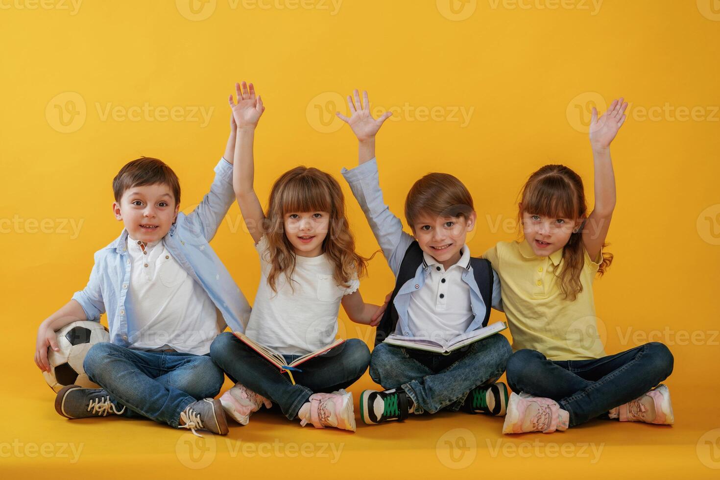 Sitting on the ,floor. Kids are together against yellow background photo