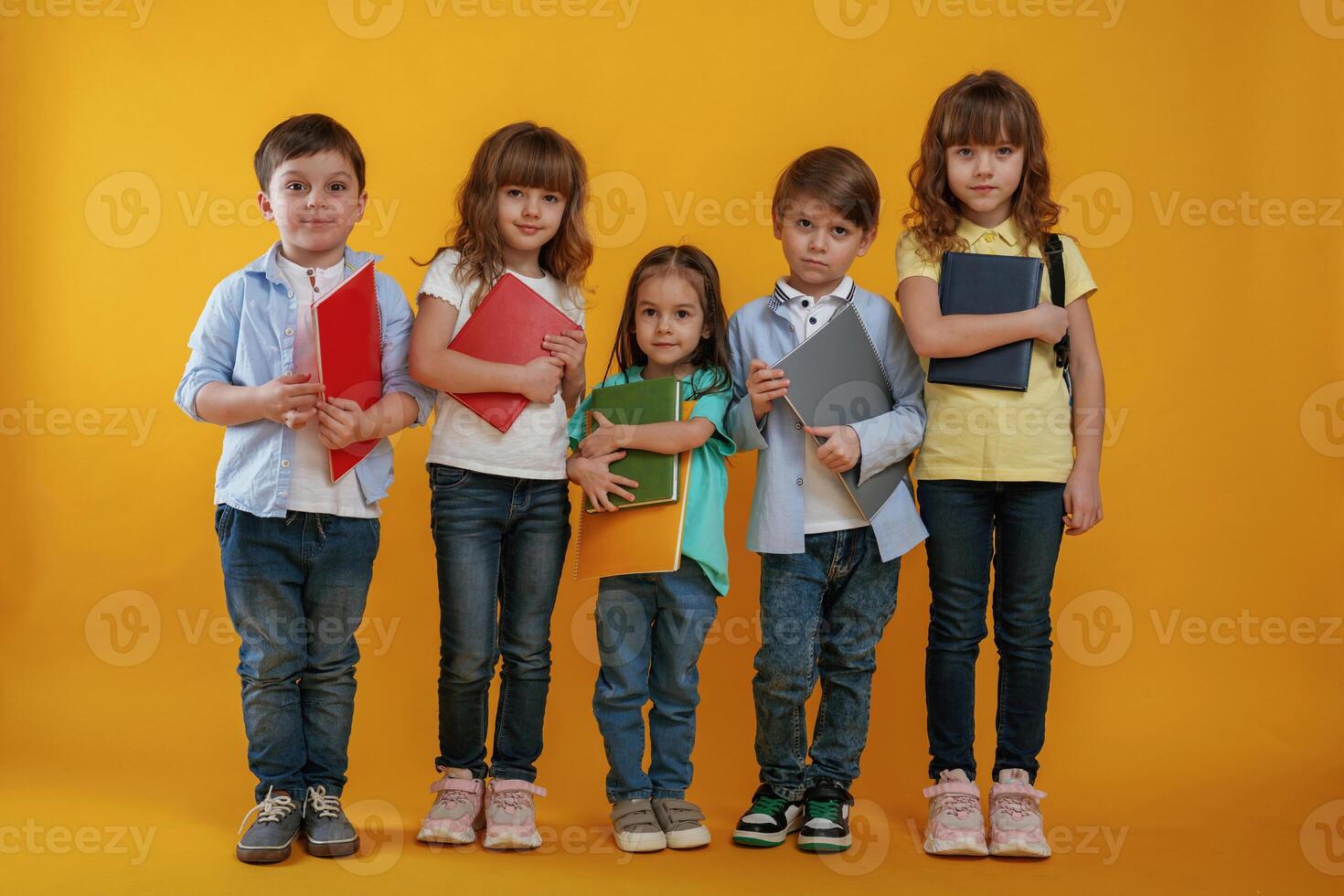 Standing and posing. Kids ,are together against yellow background photo