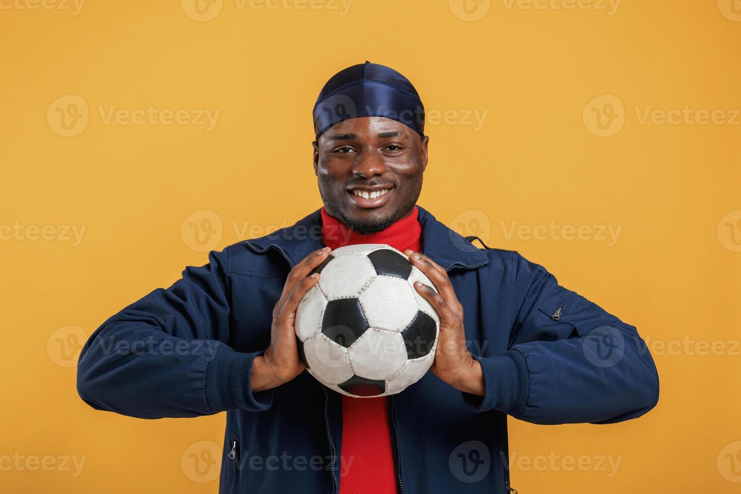 Holding soccer,, ball. Handsome black man is in the studio against yellow background photo