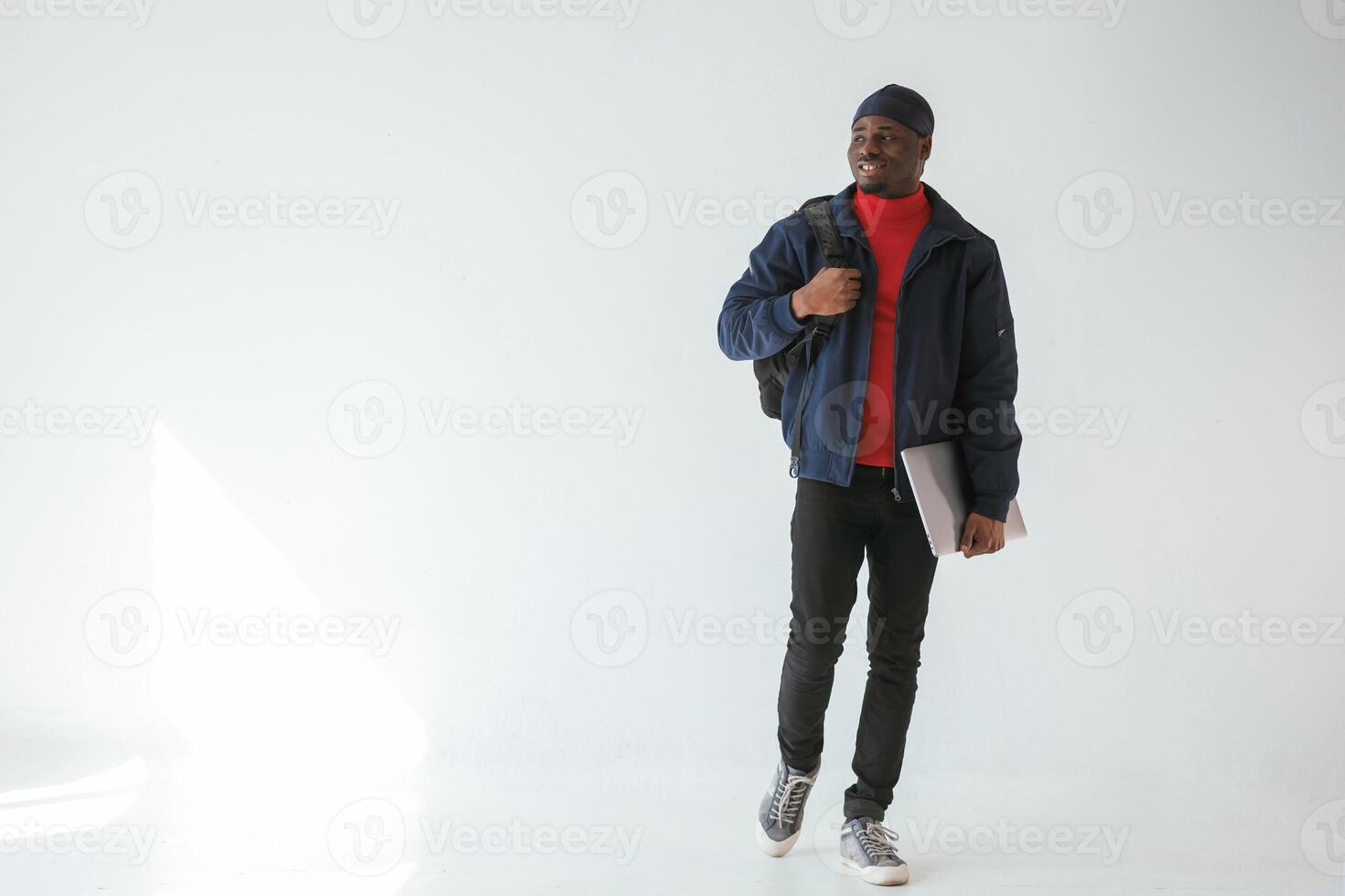Front view, with laptop. Black ,man ,,in cap is in the studio against white background photo