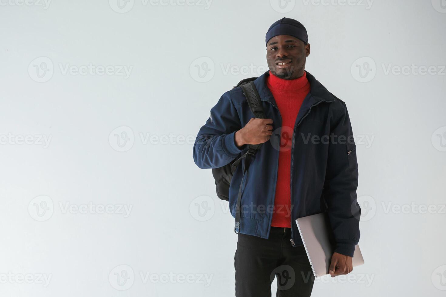 Front view, with laptop. Black man in cap is ,in the studio against white background photo
