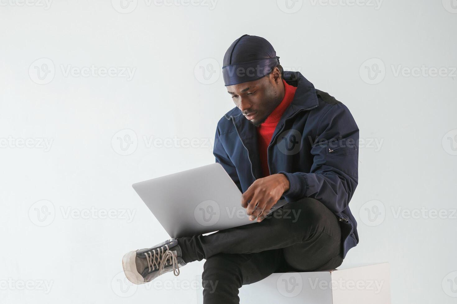 Front view, with laptop. Black man ,in, cap is in the studio against white background photo