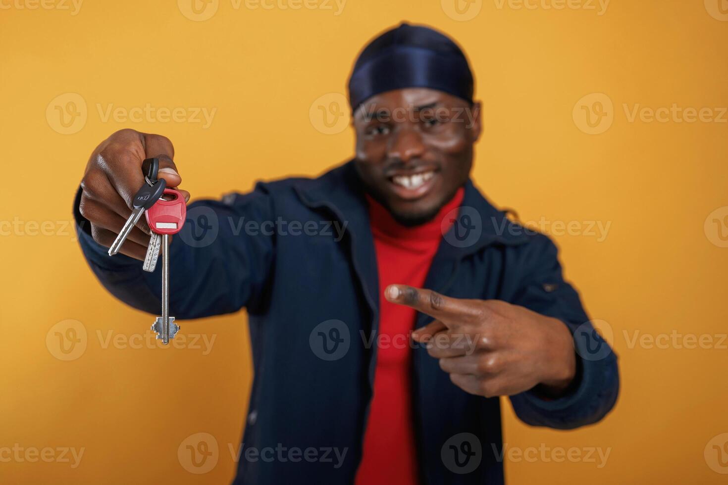 Keys for new home in hand, happy... Handsome black man is in the studio against yellow background photo