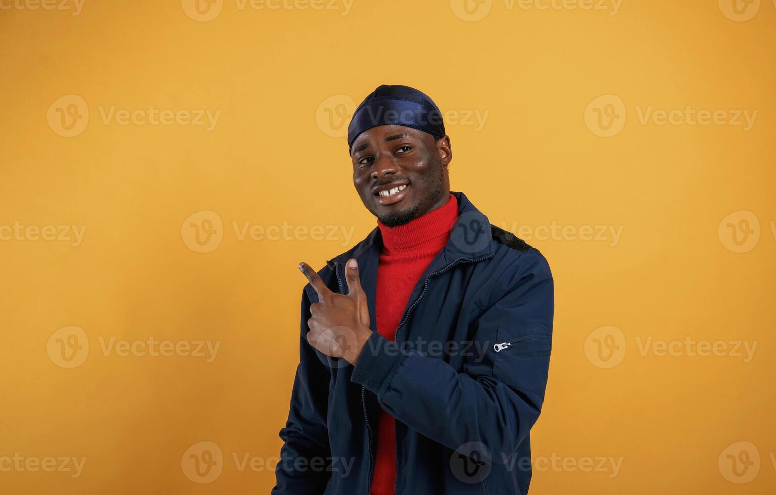 Pointing by ,the finger to copy space. Handsome black man is in the studio against yellow background photo