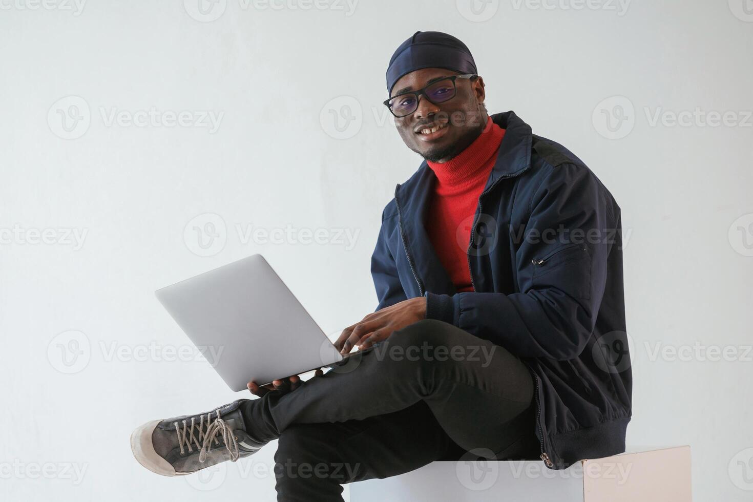 Front, view, with laptop. Black man in cap is in the studio against white background photo