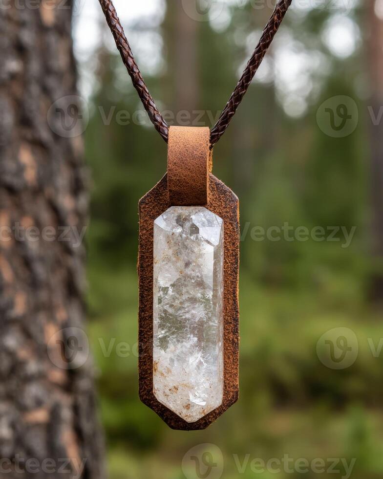 A clear quartz crystal point pendant hanging in a forest photo