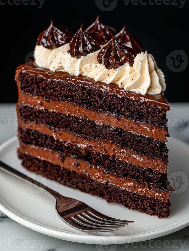A slice of decadent chocolate layer cake with frosting and a fork on a plate photo