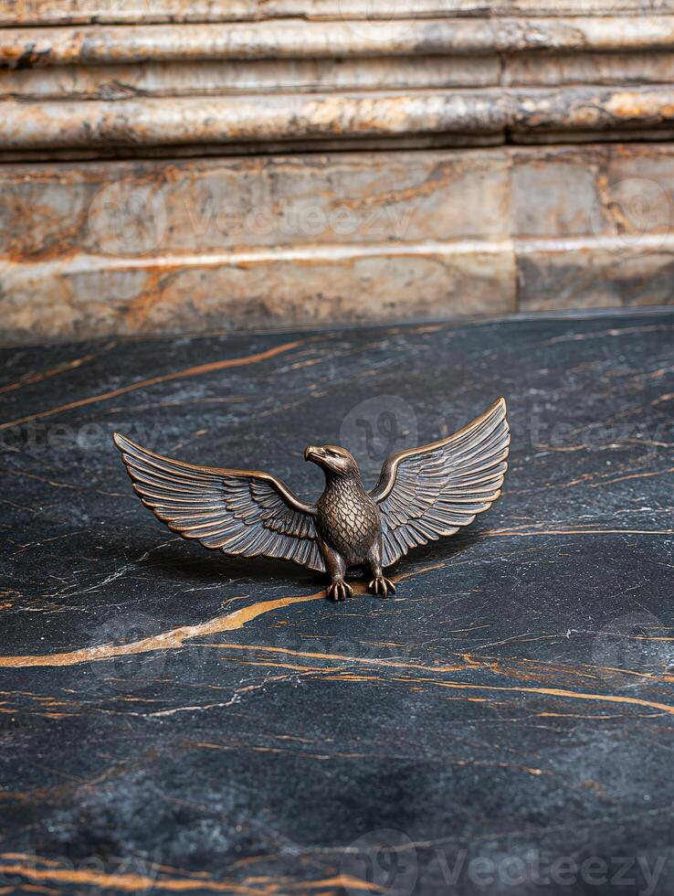 Bronze eagle statue with outstretched wings on marble surface photo