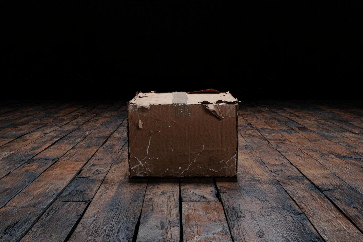 A worn cardboard box sits on a rustic wooden floor photo