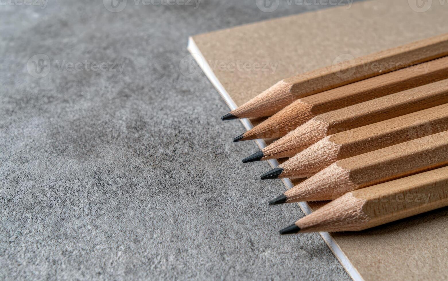 Sharpened pencils resting on a brown notebook, ready to write photo