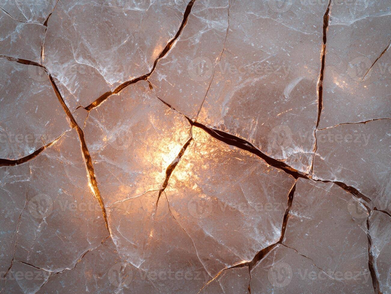Cracked ice surface with golden light shining through photo