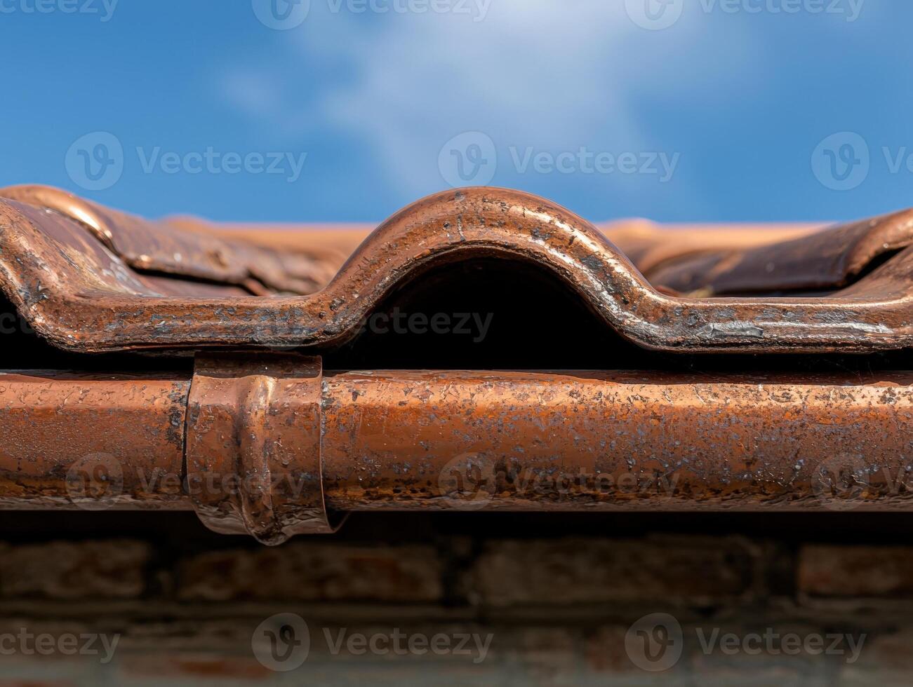 Weathered copper gutter and roof tiles against a blue sky photo