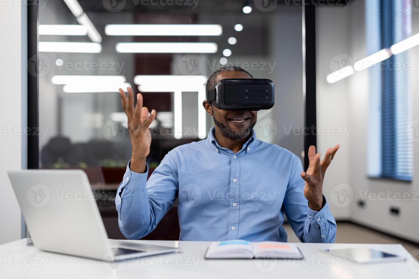 Mature african american businessman using virtual reality headset in office. Enthusiastically gesturing while exploring digital world. VR technology enhancing business creativity and strategy. photo