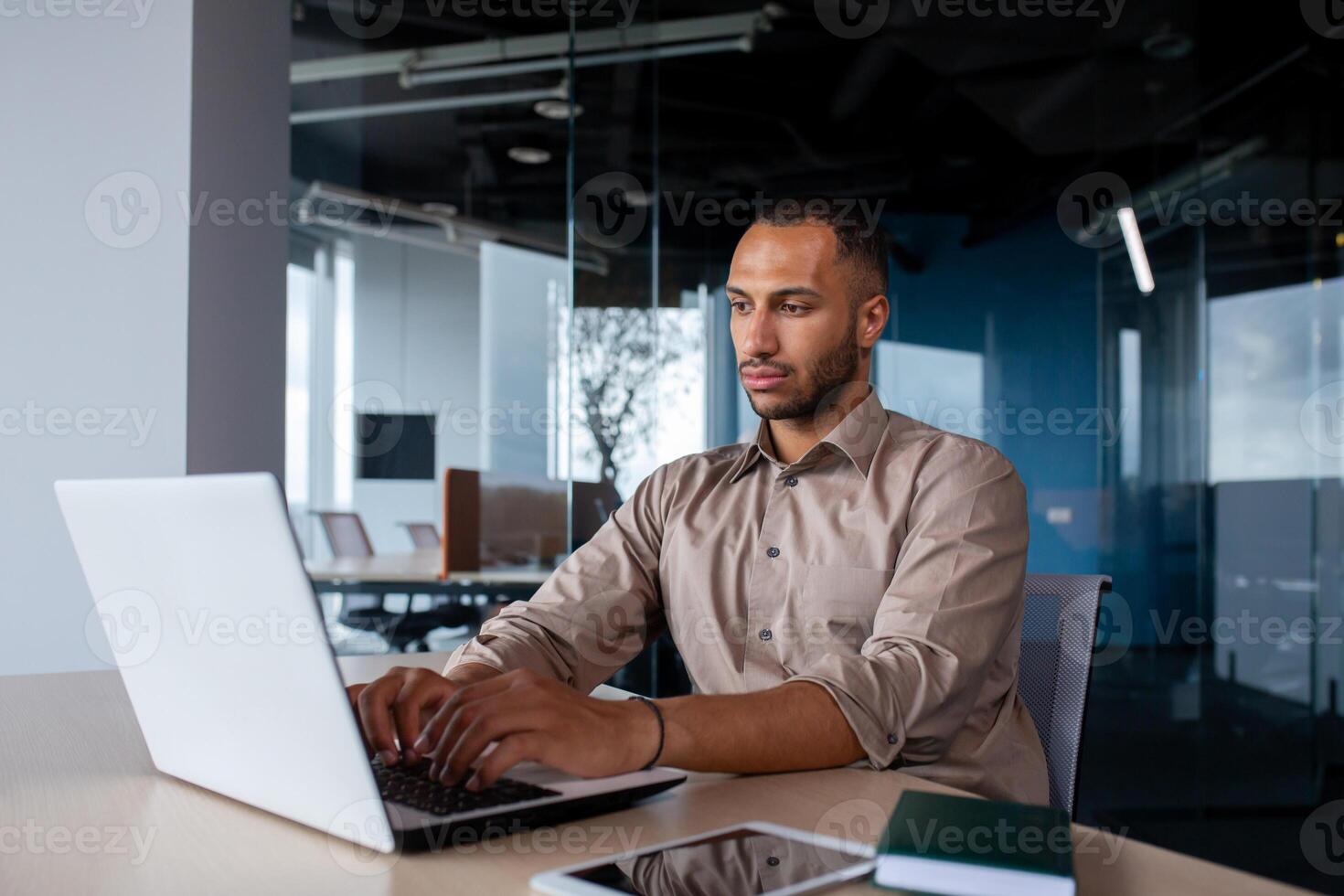Serious concentrated man working inside office at workplace, businessman typing on laptop keyboard, programmer developing new software. photo