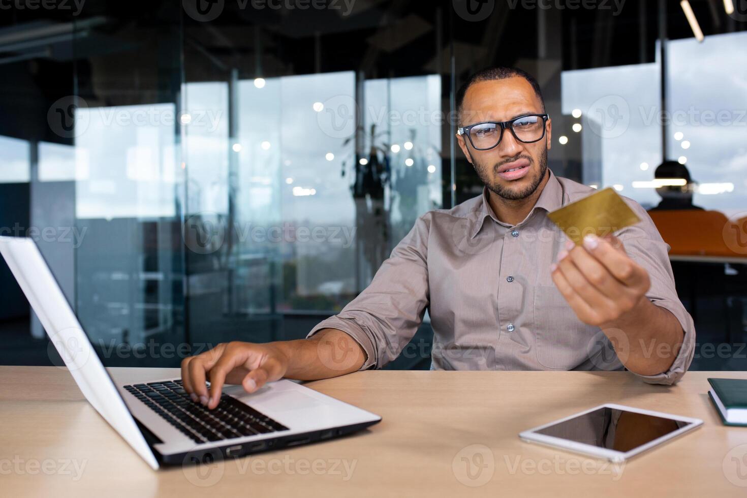 Businessman inside office trying to make a purchase in an online store, the man received an error in the transfer of funds for the order of the product, online fraud, disappointed looking at camera. photo